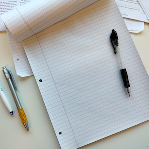 a pen laying on a lined notepad, ready for use