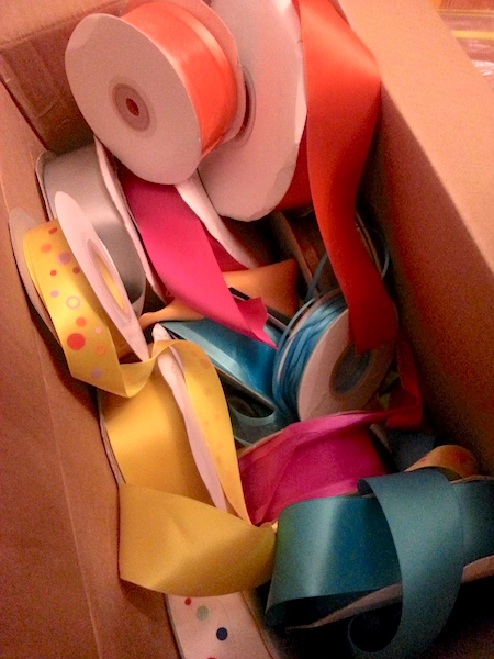 open cardboard box filled with rolls of colorful satin ribbon