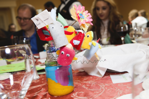 monster finger puppets sticking out of a jar on top of a little wire tree, on a table