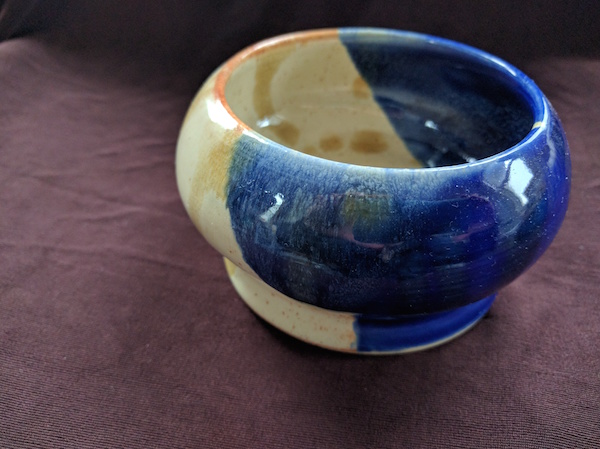 side view of a blue and off-white glazed bowl, middle roundly bulging out
