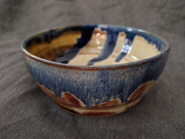 marbled clay bowl seen from the side and top, blue on the rim dripping down to mix with the brown and white sides