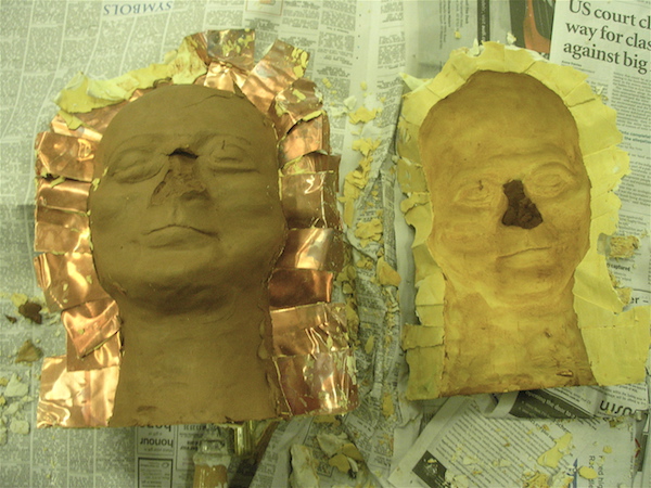 front half of the mold sits empty on the right; on the left, most of the clay head rests intact in the back half