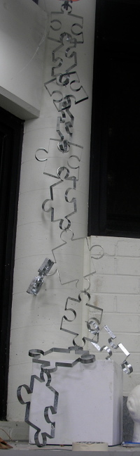 Chain of steel puzzle piece frames connected end-to-end and hung from ceiling