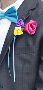 ribbon flower boutonniere attached with a pin to a suit jacket pocket