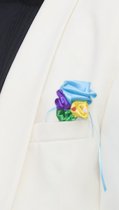 ribbon flower boutonniere attached with a pin to a suit jacket pocket