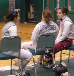 three VC women foilists sitting in green chairs, backs to the camera