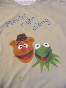 close up of t-shirt with text movin' right along and painted pictures of fozzie bear and kermit the frog