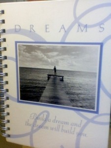 spiral bound periwinkle-blue notebook, photo on the front and the words "DREAMS: Build a dream and the dream will build you"