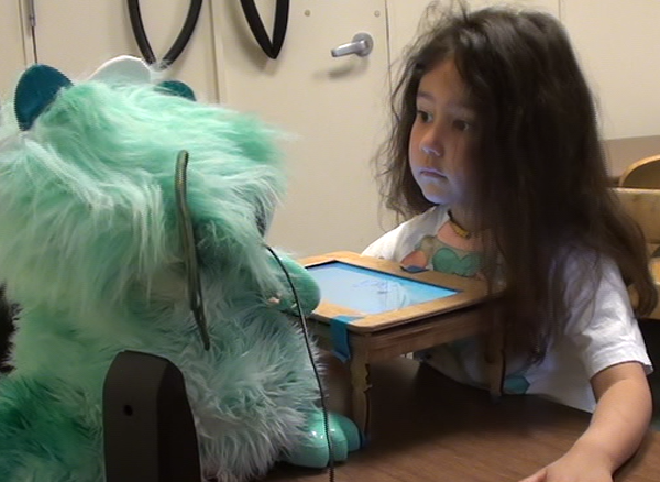 Girl looking intently over a mini table at a dragon robot